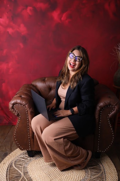 Sueli Braga sorrindo com o notebook no colo, em ensaio fotográfico
